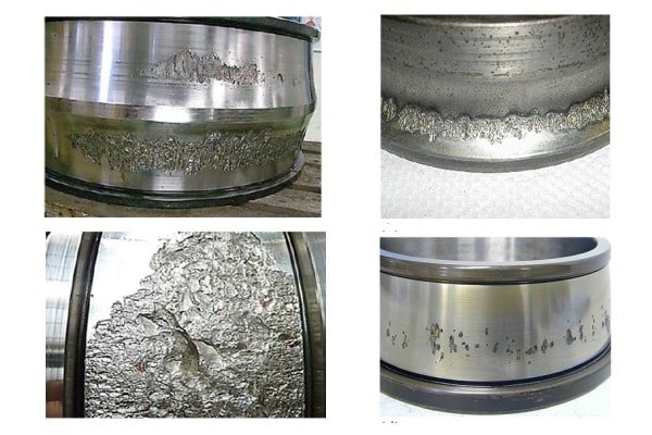 Close-up of a steel bearing raceway showing early signs of surface material removal and cavity formation.