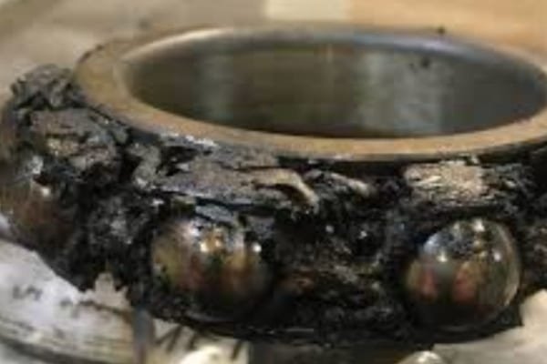 Visual comparison of fresh grease versus black, carbonized grease damaged by high-temperature electrical discharges.