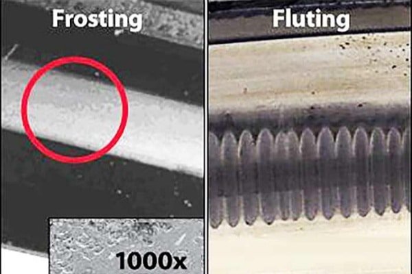 Microscopic view of a bearing raceway showing electrical pitting craters and dull grey frosting compared to healthy steel.