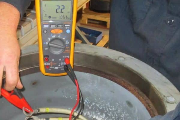  A maintenance technician performing a Megger test on a traction motor bearing to verify insulation resistance is above 50 Megaohms.