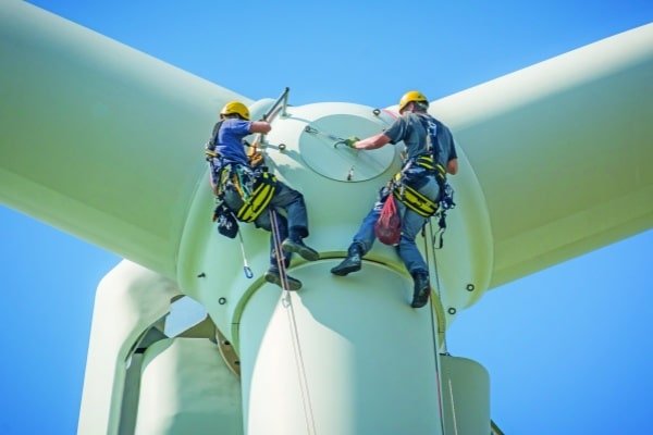 Wind Turbine Insulated Bearings: Preventing Generator Failure & WEC Technicians performing maintenance on a wind turbine generator nacelle overlooking an offshore wind farm.